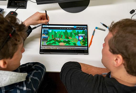 Image of two students working on a tablet that depicts a game design.